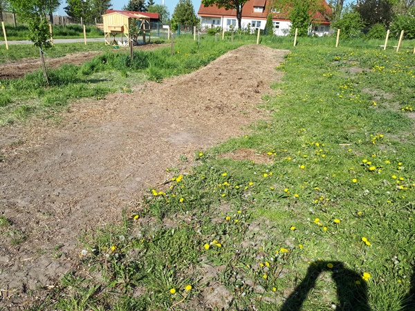 Small field with a compost bed and some fruit trees